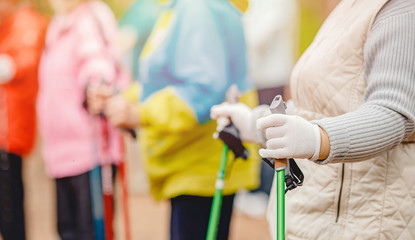 Older women are engaged in Nordic walking, close-up hands with sticks. Sports concept in park