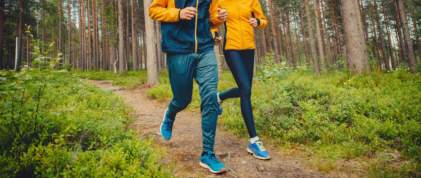 Couple running forest trail. Fitness fast movement stretching training park