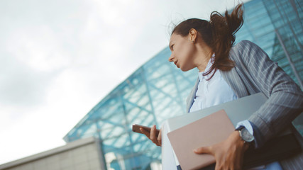 Young ambitious woman with a laptop in her hands on the background of the business center.