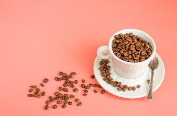 Coffee beans are filled in a white Cup on a pink background.