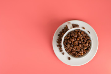 Obraz premium Coffee beans are filled in a white Cup on a pink background.