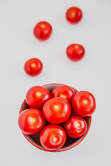Cherry tomatoes in a bowl on white background. Selective focus. High key photo. Top view.