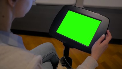 Green screen, mock up, education, copyspace, template, chroma key, technology concept. Woman looking at floor standing tablet kiosk with blank green display at exhibition or museum - close up view