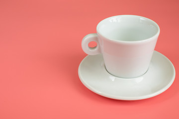 Minimalism white empty Cup with saucer on pink background.