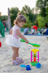 little baby girl playing in the sandbox in kindergarten