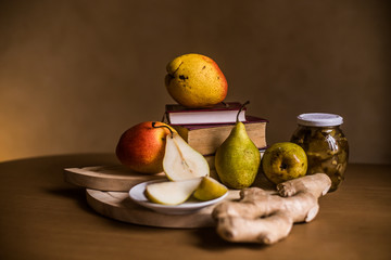 The photo shows fresh pears, a jar of jam and ginger root on the background of the tablecloth.