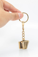 Mano sosteniendo un llavero de acordeon de oro o metal