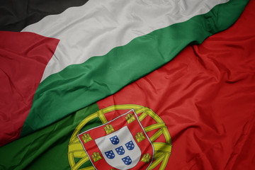 waving colorful flag of portugal and national flag of palestine.