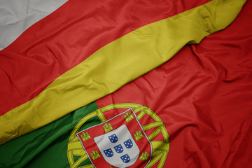 waving colorful flag of portugal and national flag of south ossetia.