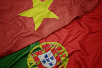 waving colorful flag of portugal and national flag of vietnam.