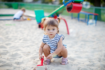 little baby girl playing in the sandbox in kindergarten