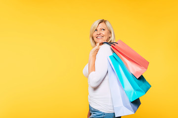 Buyer. Consumer. Sale. Customer. Online Shopping. Happy laughing blonde senior woman with colorful paper shopping bags is posing and has a fun after good visit of mall. Banner photo