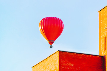 Red air balloon flying over residential house building