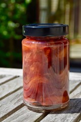 jar of delicious coarse home made plum jam on garden table