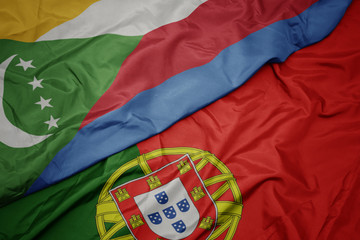 waving colorful flag of portugal and national flag of comoros.