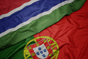 waving colorful flag of portugal and national flag of gambia.