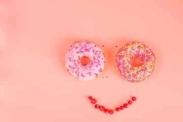 Round pink donuts on pink background with red cranberry berries.