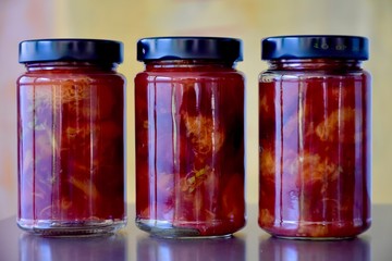 three glass jars in a row with delicious coarse home made plum jam