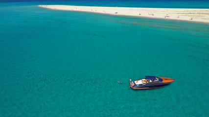 Aerial drone photo of luxury yacht docked in tropical Caribbean bay with turquoise open ocean sea