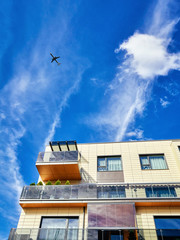 Modern residential building and jet airplane in the blue sky