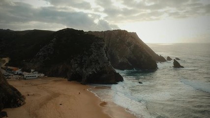Aerial view from a sandy beach at the sunset with an amazing cliff. Adraga beach Sintra, Portugal