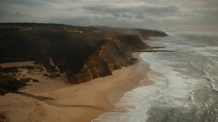 Aerial view of the Sao Juliao beach in Sintra, Portugal. Beach of Atlantic ocean with high cliffs of coastline. Drone view