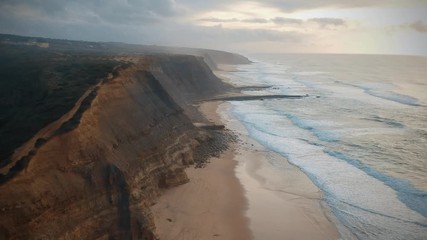 Aerial view of the Sao Juliao beach in Sintra, Portugal. Beach of Atlantic ocean with high cliffs of coastline. Drone view