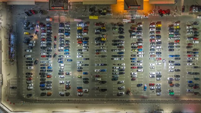 Aerial top view of the supermarket (hypermarket or shopping mall) parking lot with lots of cars at night. Time lapse. Hyperlapse