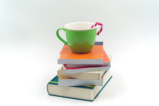 grüne Tasse mit Zuckerstange auf einem Bücherstapel.