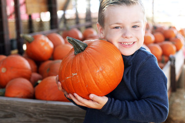 boy holding pumpkin in pumpkin patch