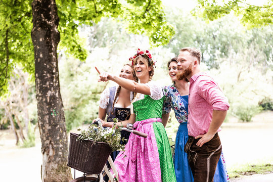 Gruppe von junge Freunden in Trachten und Dirndl l&auml;uft zum Volksfest