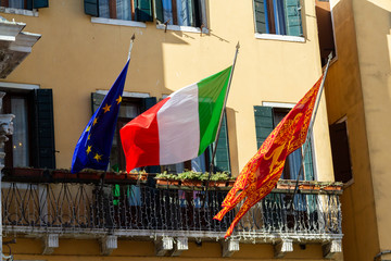 Italian, European Union's and Venice's flags hung together.	