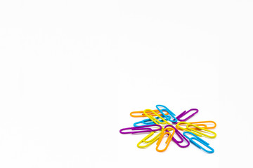 Fototapeta premium Colorful blue-yellow-orange and violet clips on a white table. Back to school