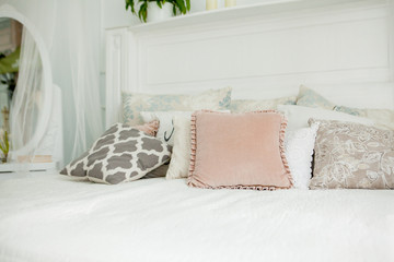 Scandinavian style white bedroom. Four pillows are on the bed. Modern interior