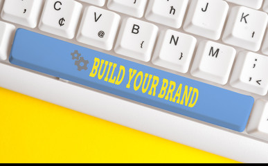 Text sign showing Build Your Brand. Business photo text enhancing brand equity using advertising campaigns White pc keyboard with empty note paper above white background key copy space