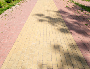 Footpath in the Park, two-tone paving slabs, shadow on the road