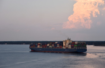 Cargo container ship arriving to the port of Norfolk, at beautiful sunset.