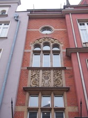 A House decorated with classical sculptures (Gdansk Poland, May 2018), red tiles, window with arches, round window, sculptures of human figures, botanical patterns, new old style