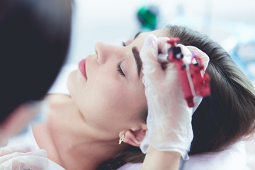 A young girl having red lips permanent makeup, micropigmentation