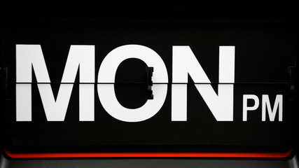 Close-up Flip clock label Monday pm. on Black background, Time concept.