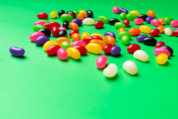 Fototapeta na wymiar colourful jelly beans candies green background Top view