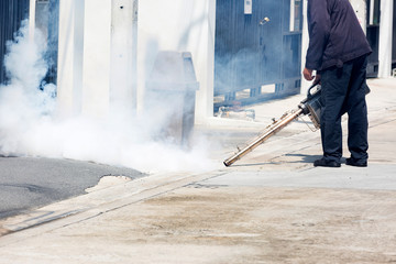 Man pointing smoke machine into manhole for pest control