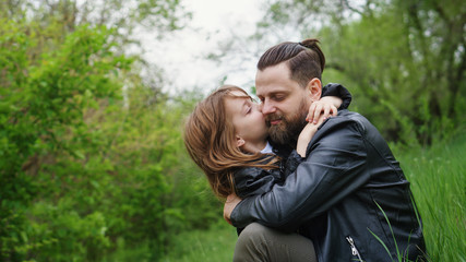 Modern stylish family walking in the park. Daughter hugs and kisses dad.Time together. Family look....