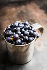 Freshly harvested blueberries in metal cup. Selective focus. Shallow depth of field.