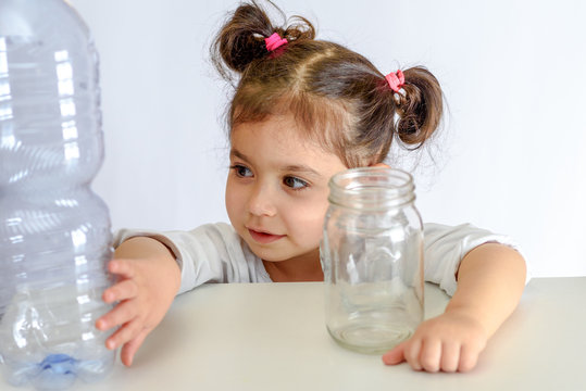 Child pushing the plastic bottle, holding glass jar. No to Plastic Containers, Yes to Glass Jars. Conceptual image for anti plastic campaign.