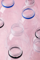 Set of diverse used empty water plastic bottles without caps on pastel pink background. Concept of recycle plastic pakaging, reuse industry, zero waste, eco-friendly