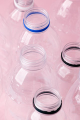 Set of diverse used empty water plastic bottles without caps on pastel pink background. Concept of recycle plastic pakaging, reuse industry, zero waste, eco-friendly