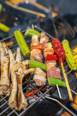 Vertical photo of skewers and chicken legs on grilling pan