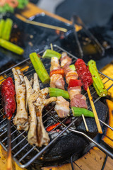 Vertical photo of skewers and chicken legs on charcoal stove