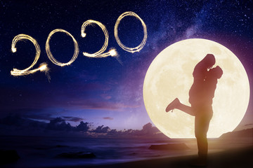 young couple kissing on beach and watching the moon.Celebrate new year 2020 concept